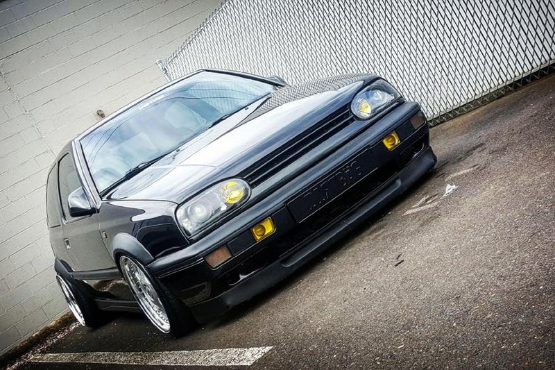 Black Volkswagen MK3 Golf with widened Euro flares, front angle view