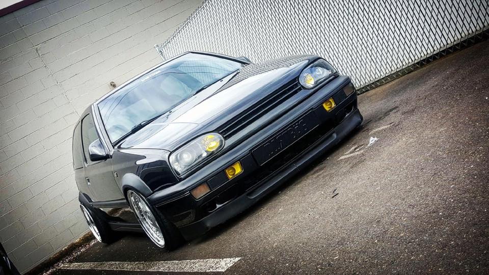 Black Volkswagen MK3 Golf with widened Euro flares, front angle view