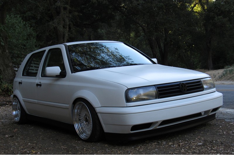 White Volkswagen MK3 Golf with widened Euro flares, front three-quarter view