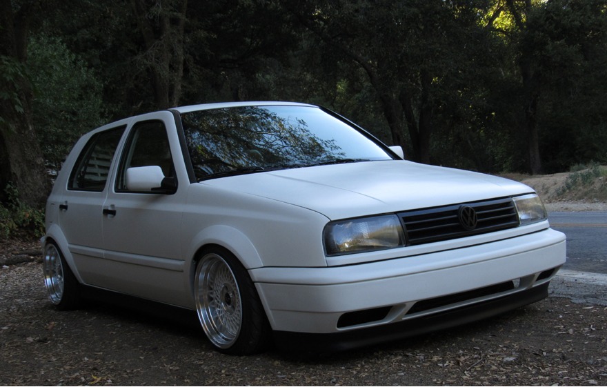 White Volkswagen MK3 Golf with widened Euro flares, front three-quarter view