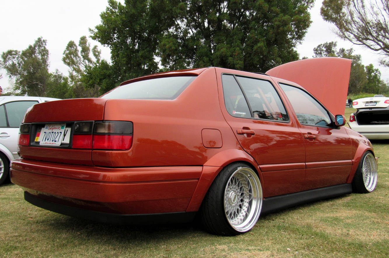 Orange Volkswagen MK3 Jetta rear view with ABT textured side skirts