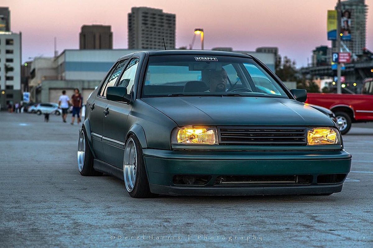 Green Volkswagen MK3 Jetta with widened Euro flares, front view at dusk