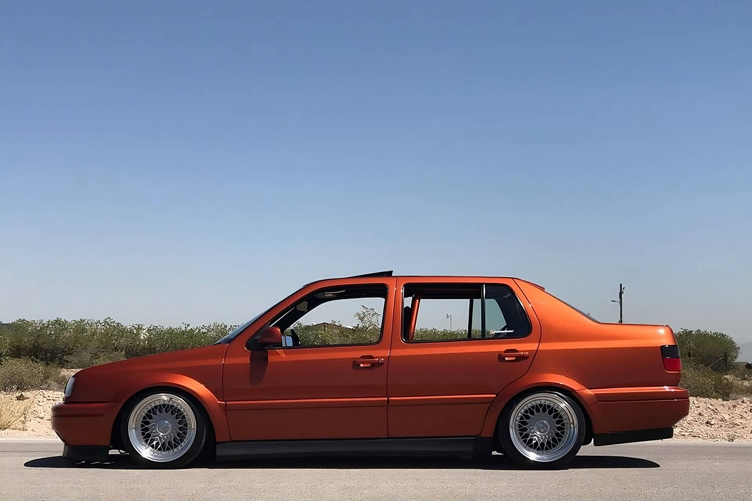 Side profile of Volkswagen Jetta MK3 Vento with wide body kit, fender flares, lowered stance and polished wheels by Optikwerks